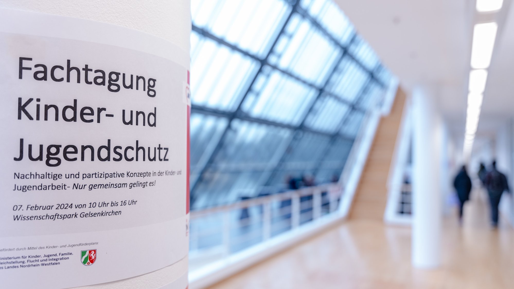Eine Säule mit der Ankündigung des Fachtages auf der Etage eines Gebäudes. Der Hintergrund ist gesoftet.
